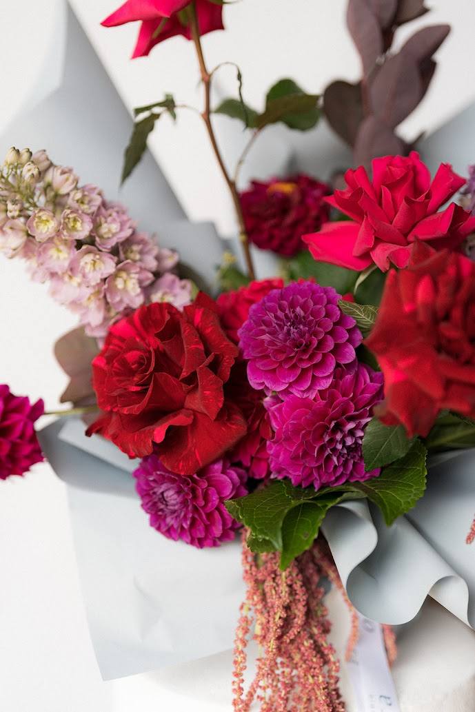 Bouquet of red and pink flowers with green leaves on a white background