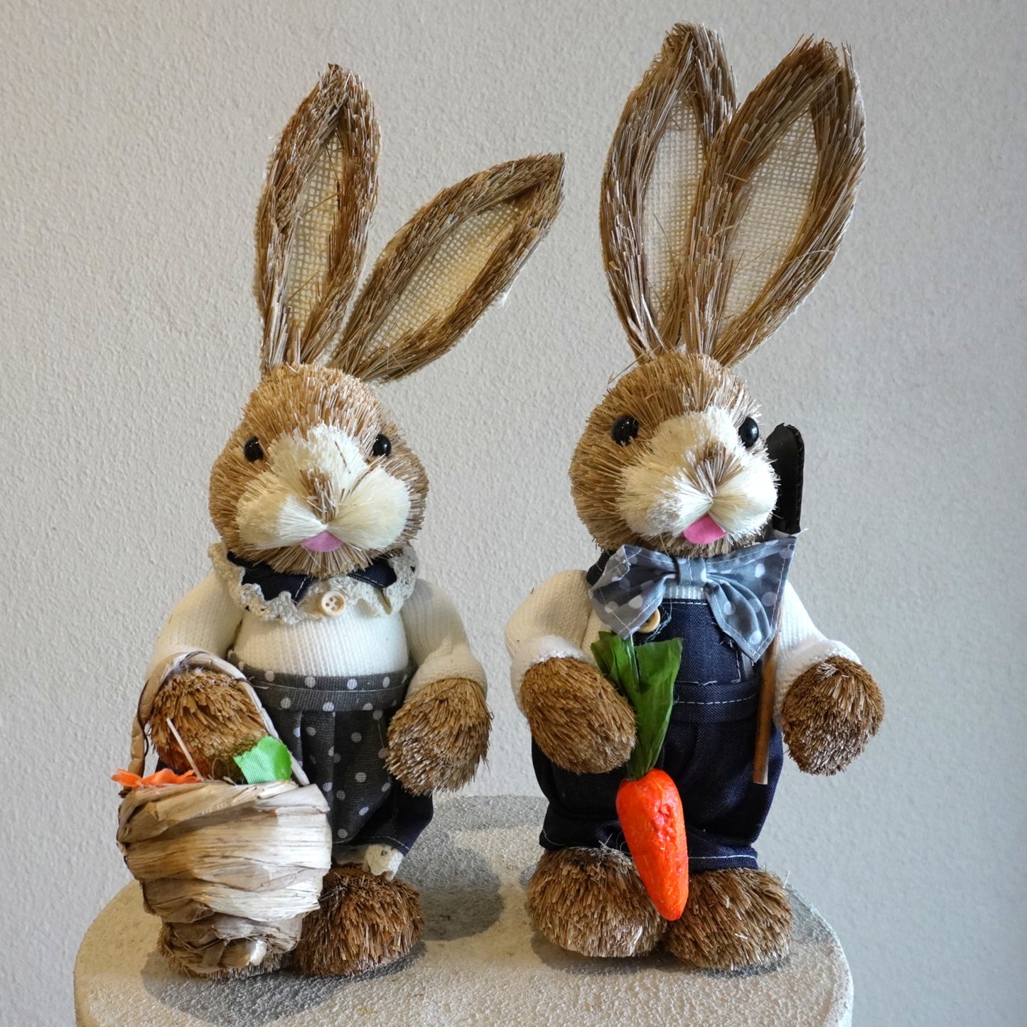 Two decorative bunnies with carrot and basket on a plain background