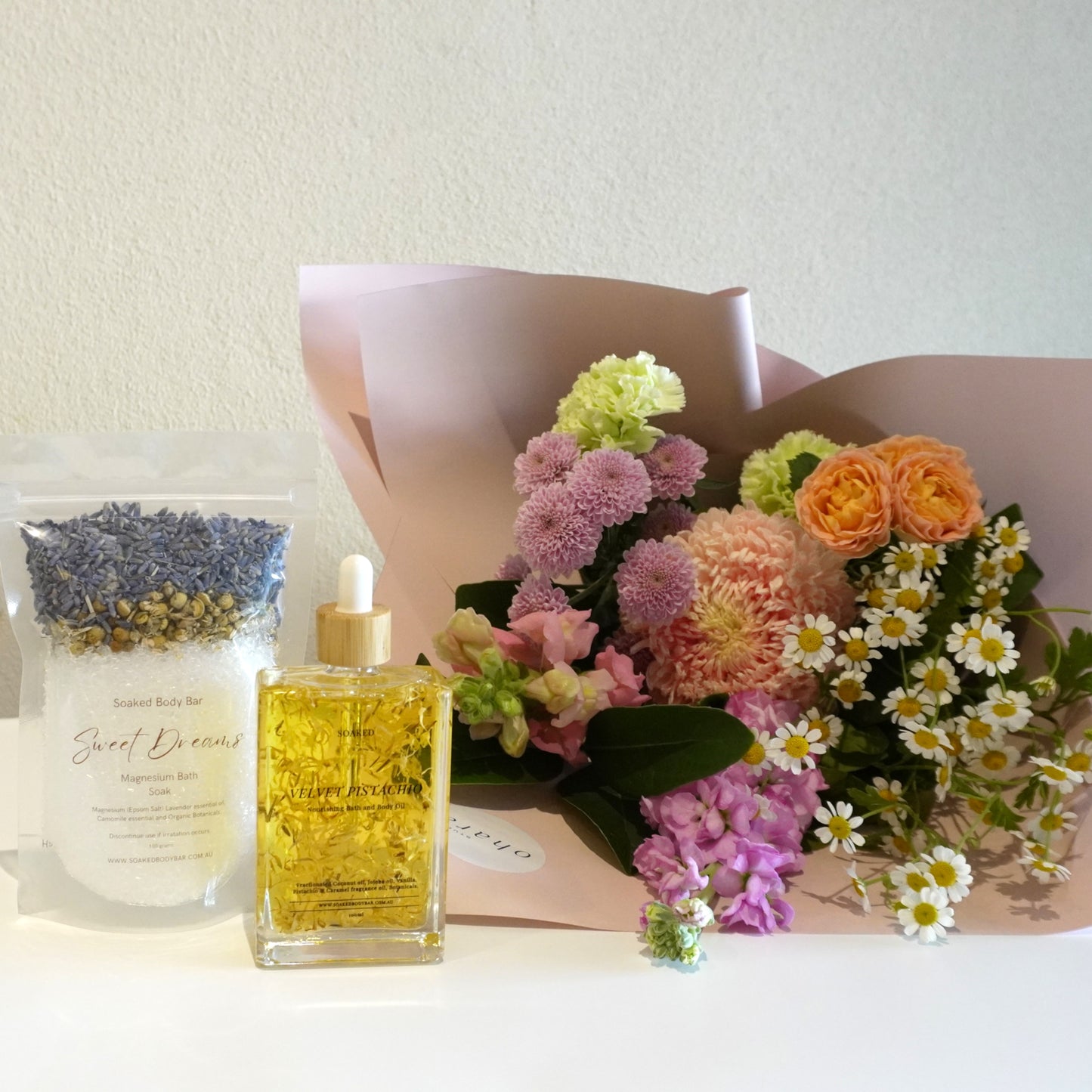 Bouquet of flowers and a bottle of oil on a white surface with a light background