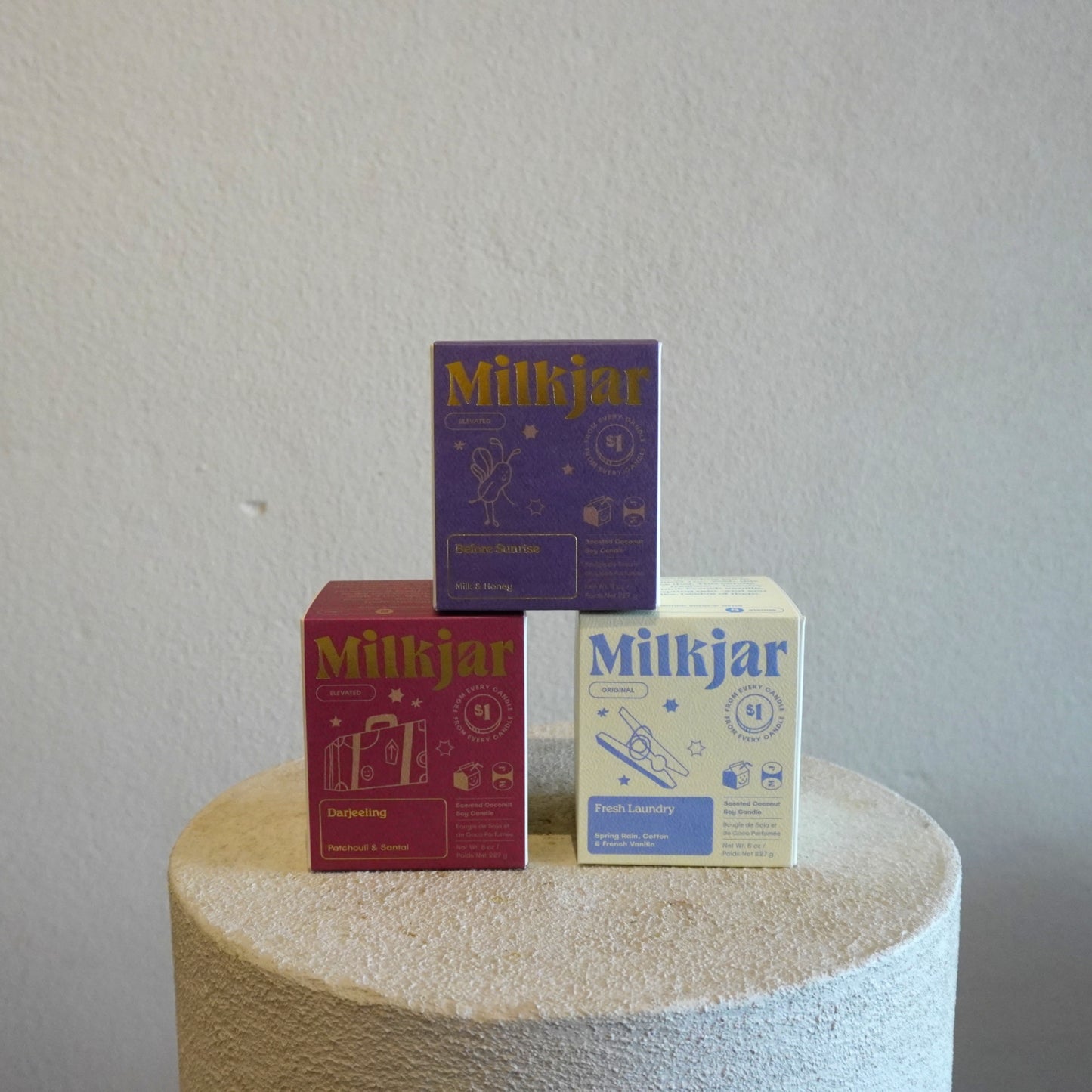 Three 'Milkjar' product boxes stacked on a textured surface with a plain background