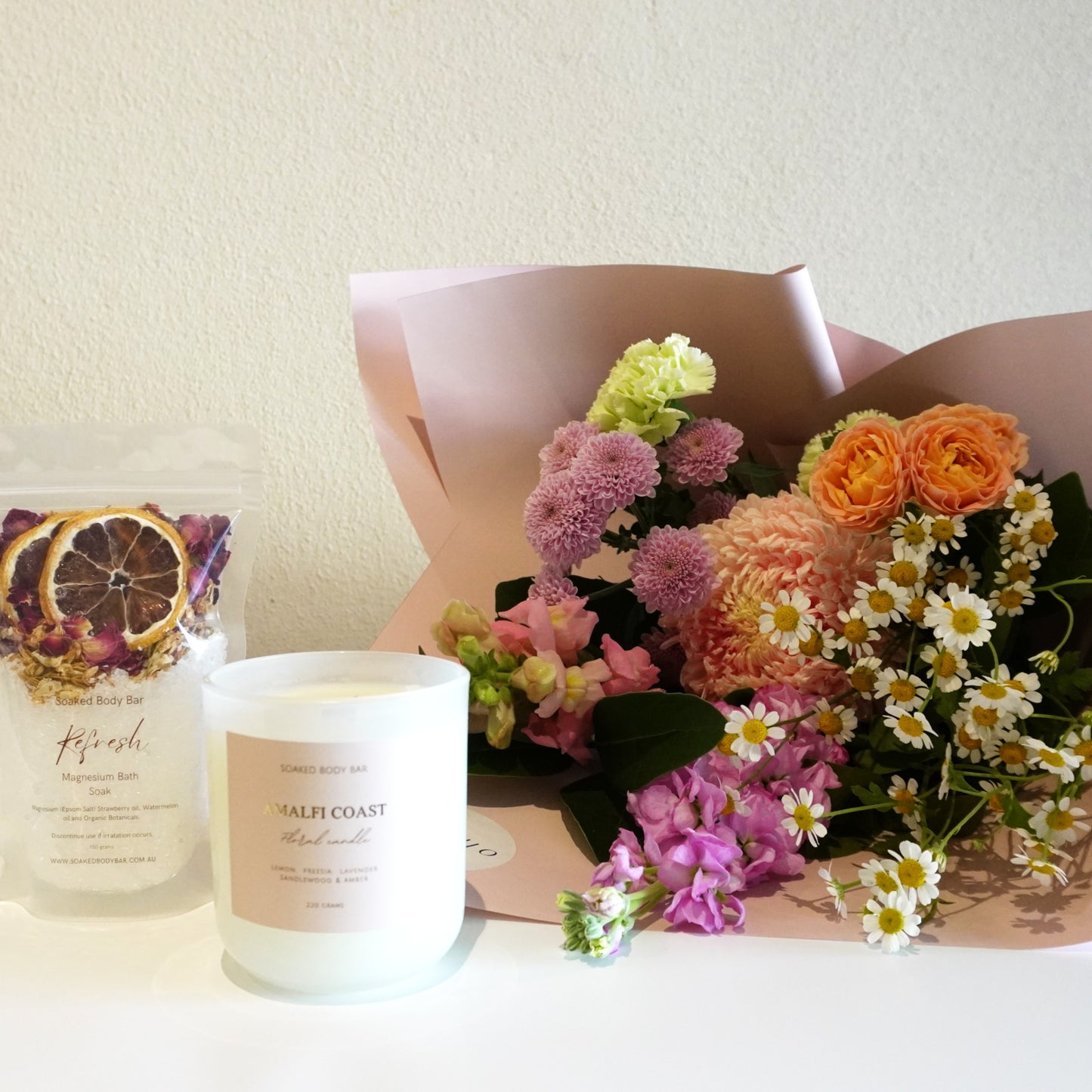 Bouquet of flowers and a candle on a white surface with a neutral background