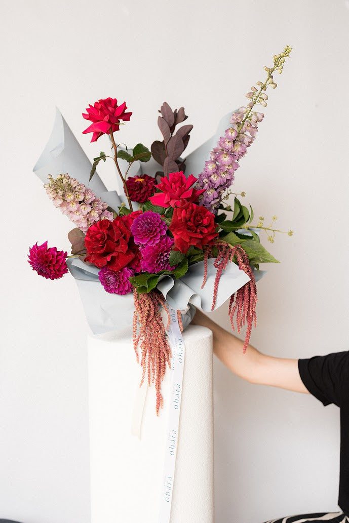 Person arranging a bouquet of flowers with a white background