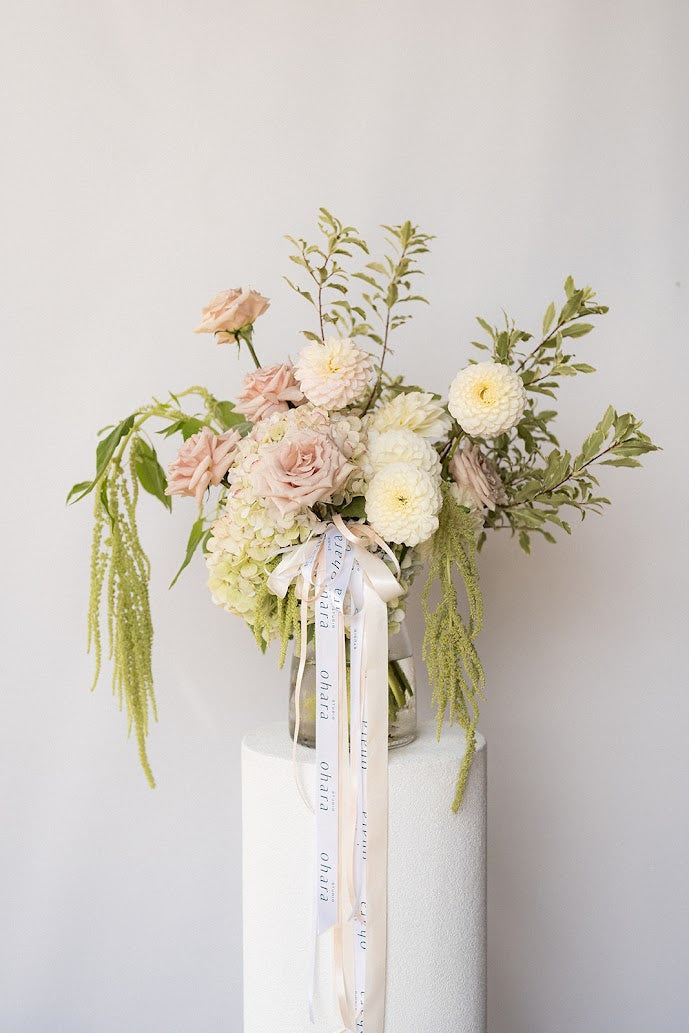 Floral arrangement in a glass vase with ribbons on a white background