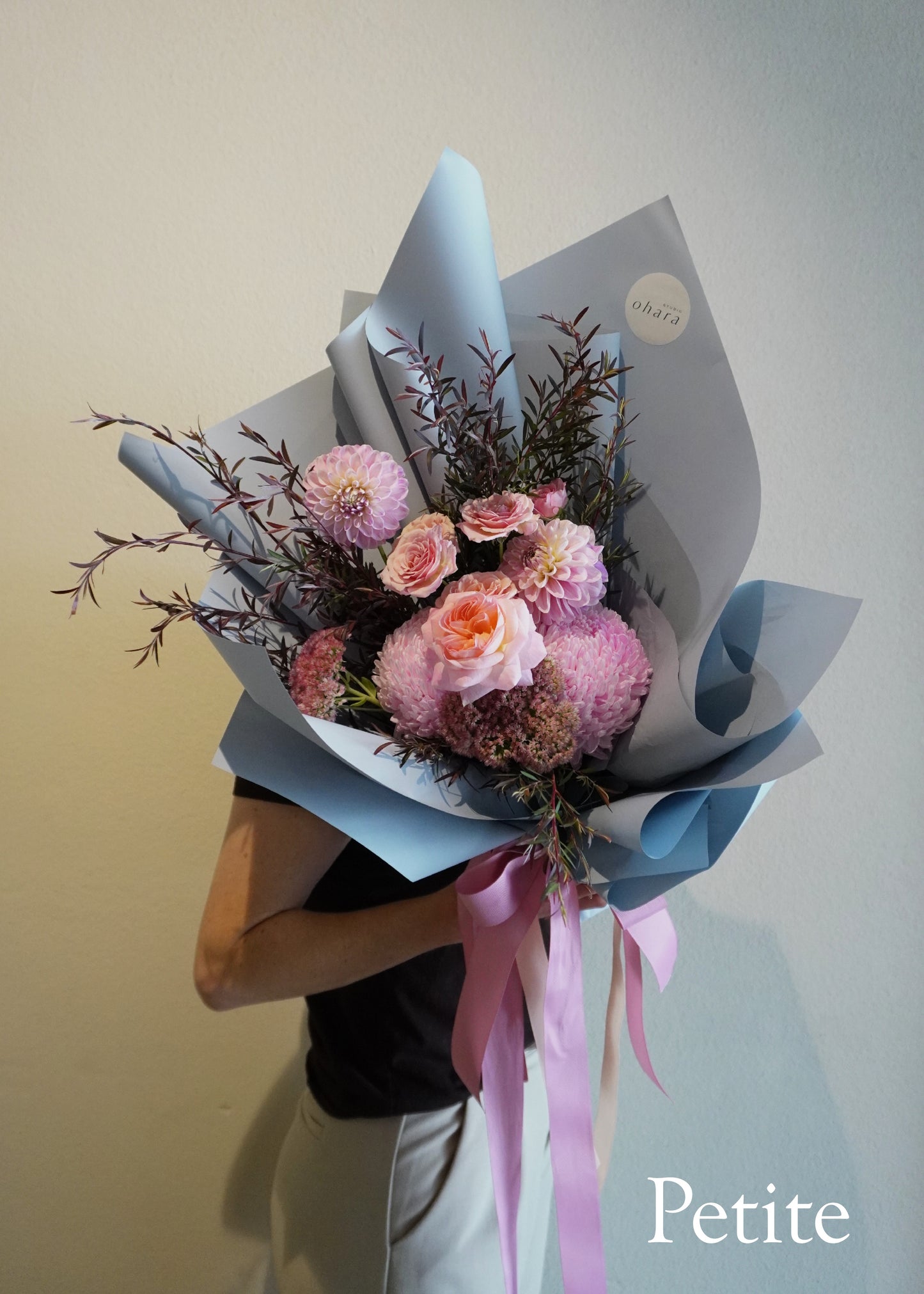 assorted pink flowers with light blue wrapping on white wall