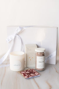 Candle, coaster, and jar of salts on a marble surface with a white background