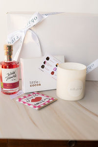 Gift set with a candle, perfume, and cards on a wooden surface.
