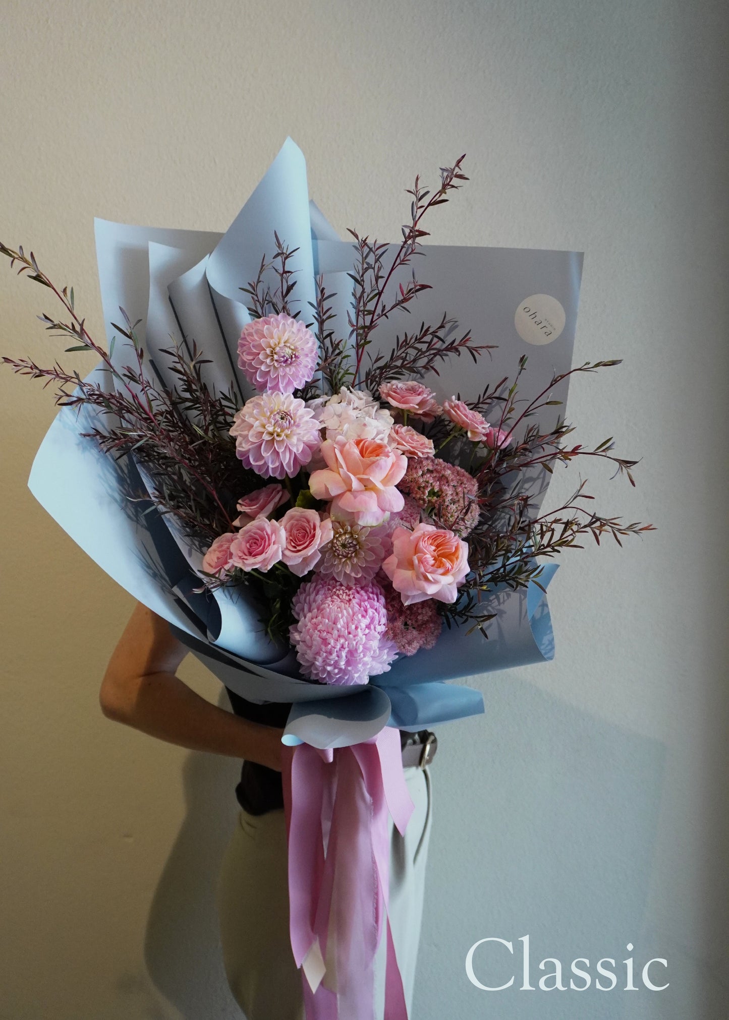 Bouquet of pink and purple flowers with a 'Classic' label on a plain background