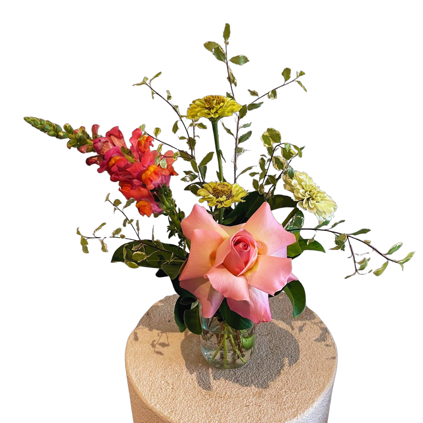 Bouquet of flowers in a clear vase on a textured surface with a white background
