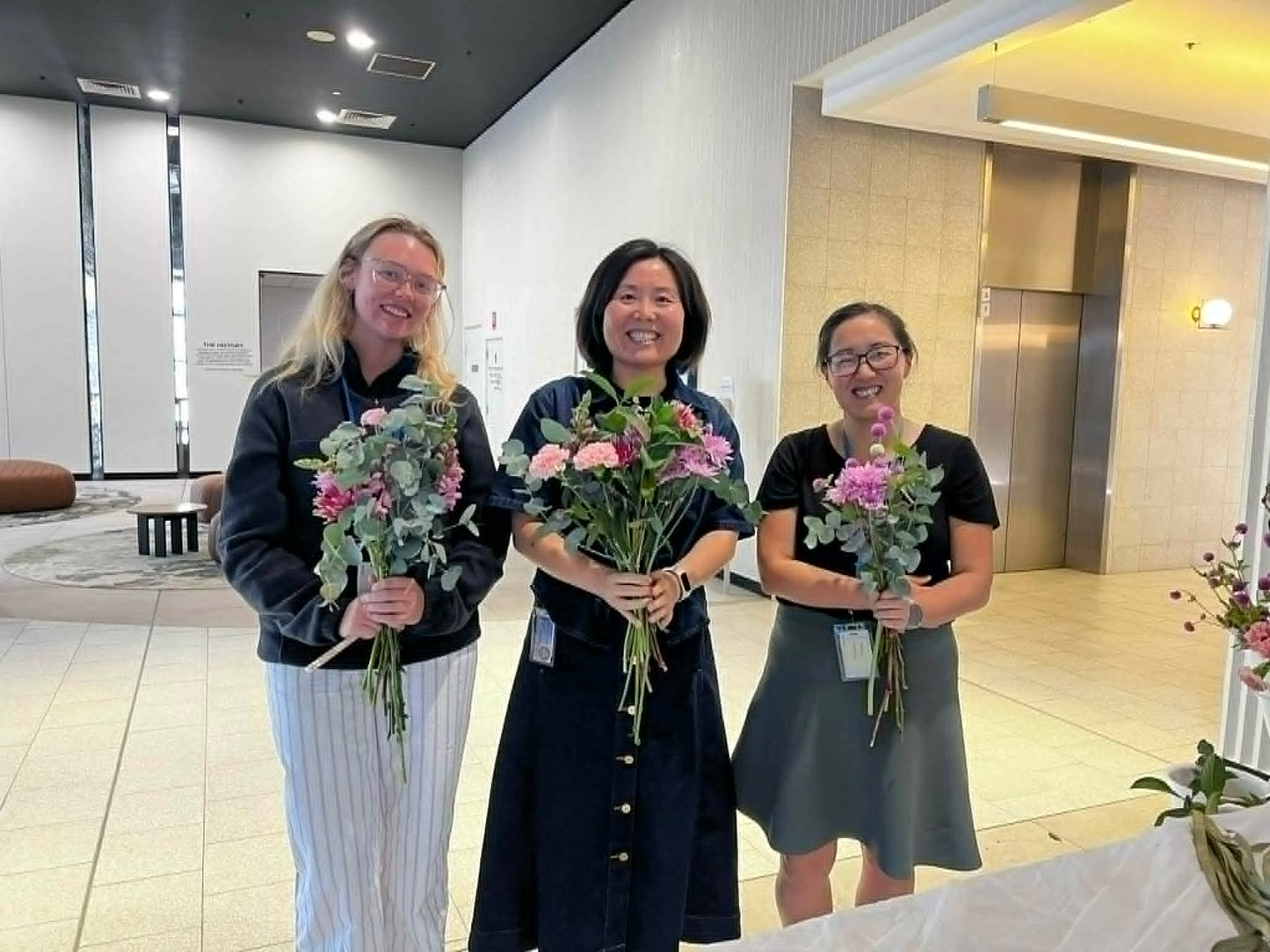 three ladies holding bouquets at work