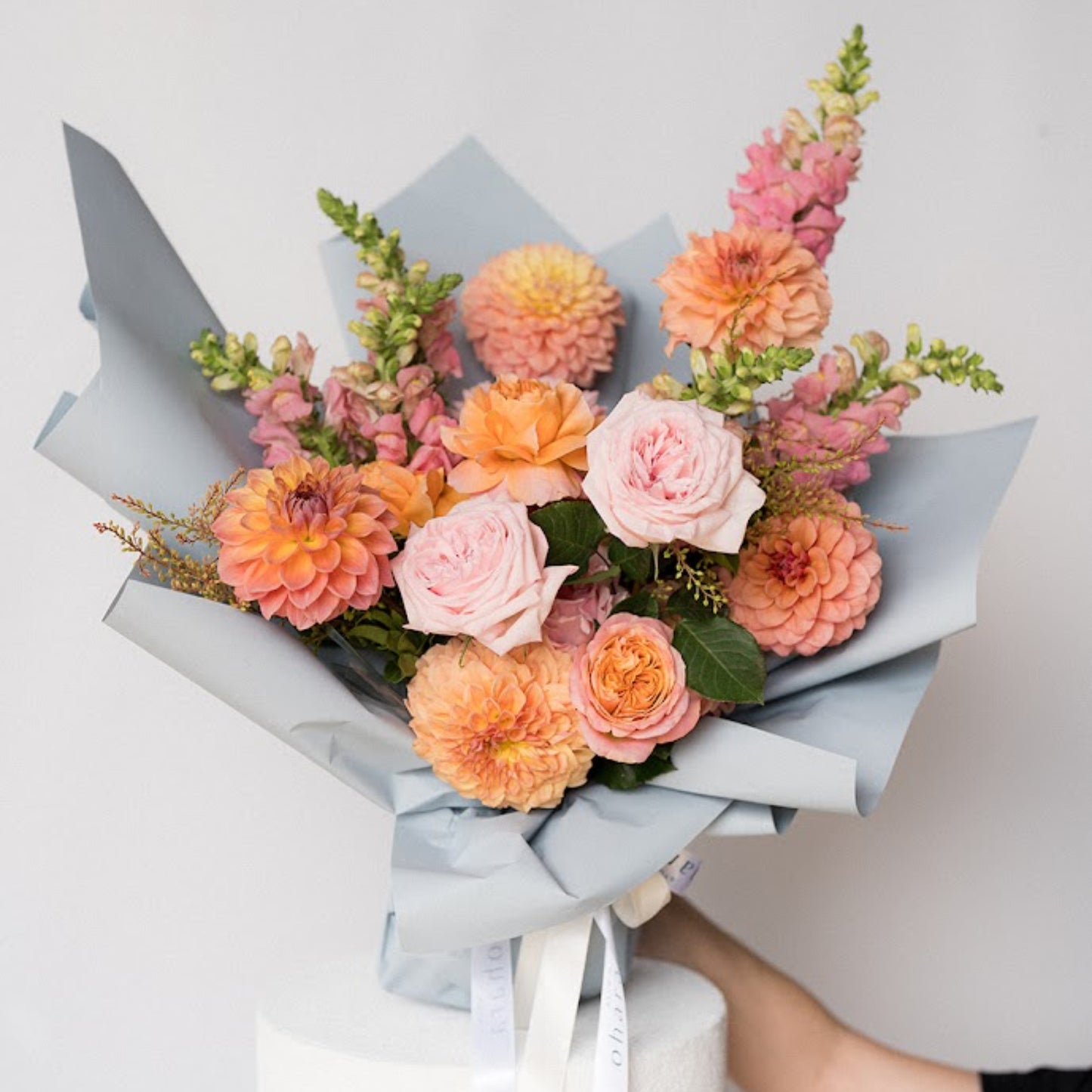 Bouquet of flowers wrapped in light blue paper on a white background