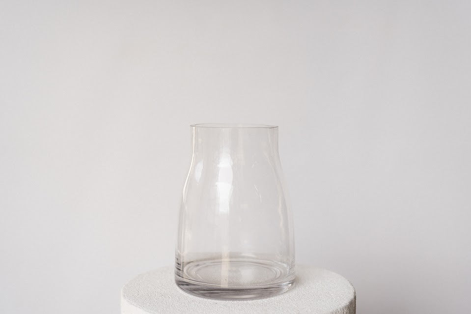 Clear glass vase on a white pedestal against a light gray background