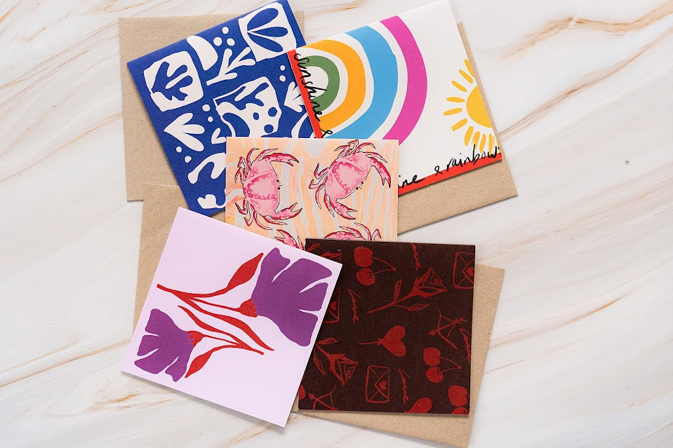 Collection of colorful greeting cards with various designs on a wooden surface