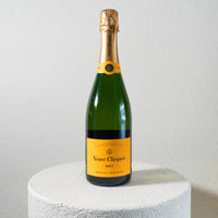 Veuve Clicquot champagne bottle on a white pedestal with a light gray background