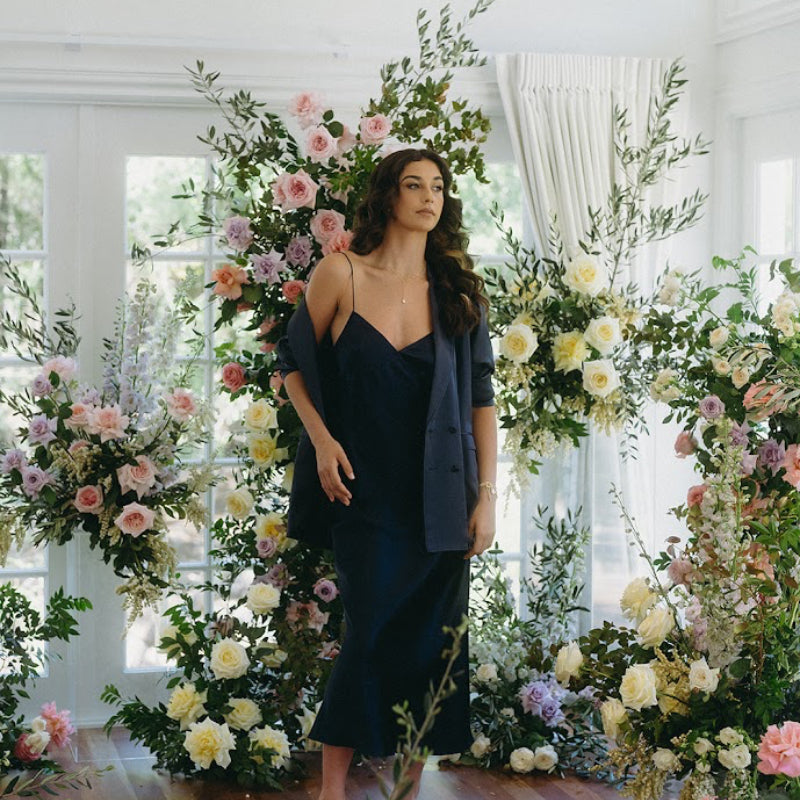 Woman standing in a room decorated with floral arches and greenery
